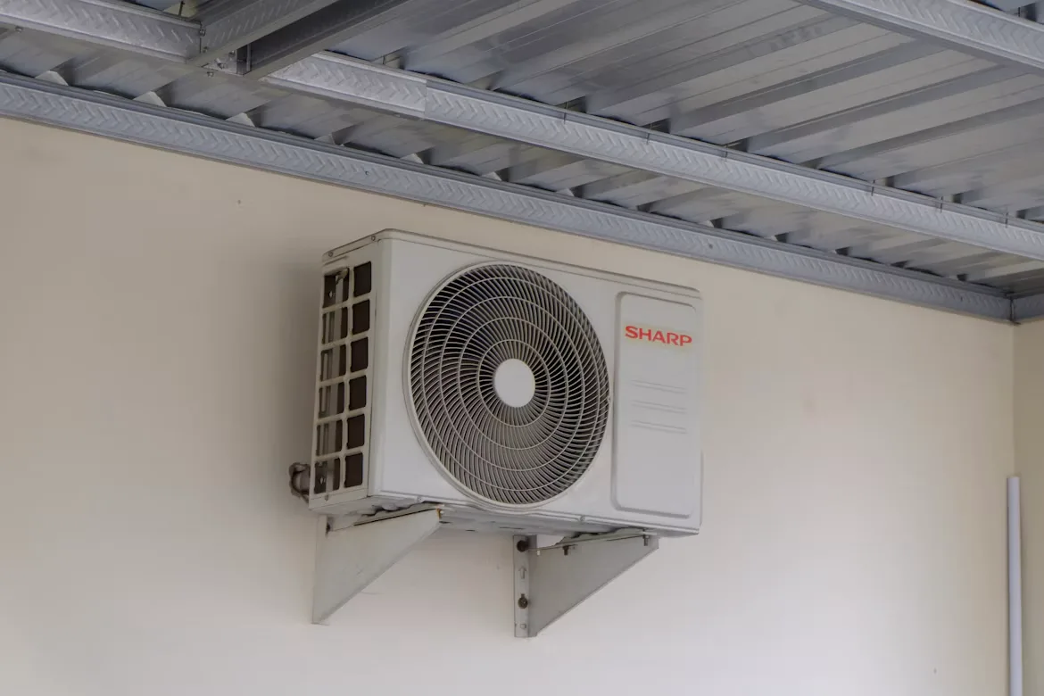 Wall-mounted outdoor air conditioning unit beneath a metal roof
